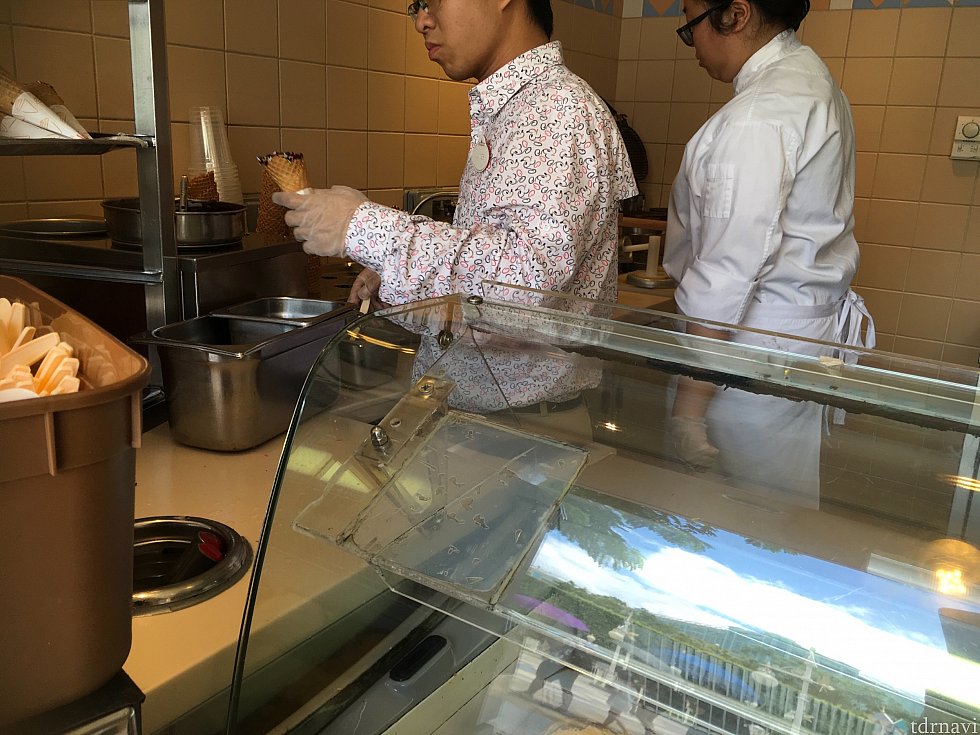 会計したら受取口へ。手前のキャストさんがコーンにチョコレートをデコレーションしている中、奥のキャストさんが熱心にエッグパフを焼いています